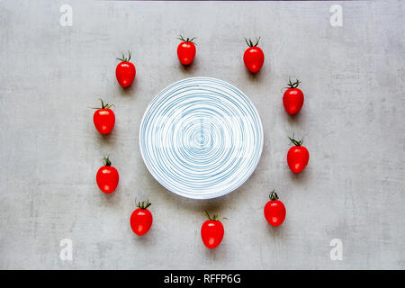 Kreative Gestaltung von frischen Tomaten und Platte auf hellen Hintergrund. Gesundes Kochen. Essen Konzept. Flach, Ansicht von oben Stockfoto