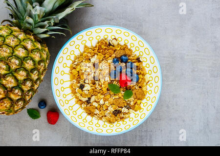 Gesundes Frühstück flach. Schüssel Müsli, Ananas und frischen Beeren. Superfood und detox Konzept. Stockfoto