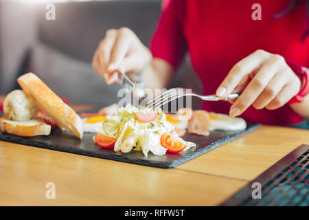 In der Nähe der Frau in rotem Kleid Essen Salat Stockfoto