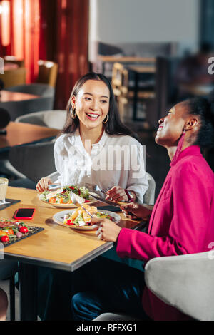 Freunde lachen, während in einem großen Restaurant Kommunikation Stockfoto