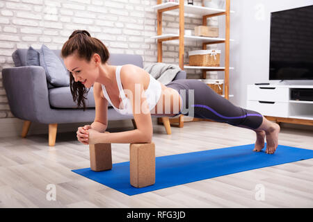 Passen junge Frau mit Holzblöcken während einer Übung auf Yoga Matte Stockfoto