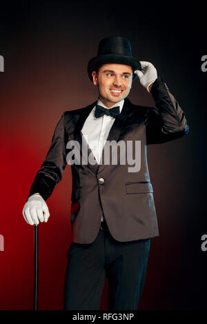 Berufliche Tätigkeit. Showman, Handschuhe und Hut stehen isoliert auf Wand mit Zuckerrohr zur Seite Suchen glücklich Stockfoto