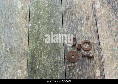 Verwitterte Palette Holz Bretter senkrecht als Hintergrund mit rostigen Schrauben, Muttern und Unterlegscheiben ausgerichtet, in der rechten unteren Ecke platziert. Stockfoto