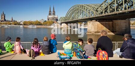 Kinder der Gruppe bei einem Picknick am Rhein Boulevard mit dem Kölner Dom und Hohenzollernbrücke im Hintergrund Stockfoto