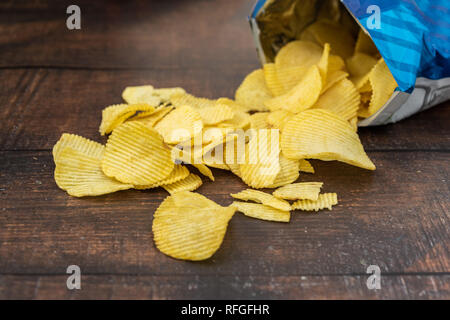 Paket der knusprige Kartoffelchips auf hölzernen Hintergrund Stockfoto