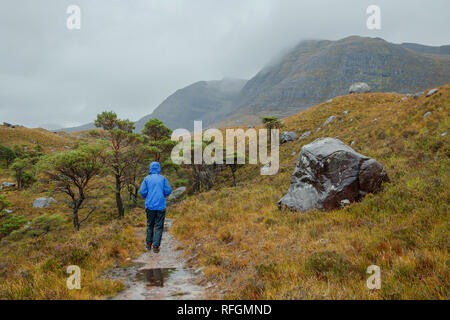 Eine Person, die in der schottischen Landschaft in der Nähe des Allt Bottighofen Rooill Fluss in Torridon, Schottland Stockfoto