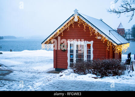 Gefrorenen See, Schnee und wenig Holzhaus mit Lichtern auf einem See in Trakai, Vilnius, Litauen Stockfoto