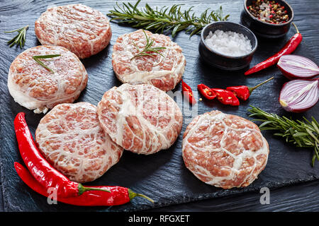 Close-up Fleischpflanzerl - raw Atriaux von Schweinefleisch in caul Fett gewickelt, Schweizer Küche, Sorte Wurst auf einem hölzernen Fach mit Gewürzen und Salz, auf einer Stockfoto