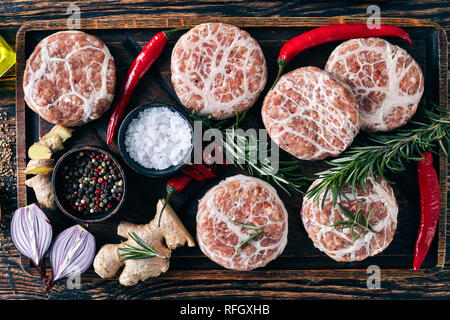 Fleisch Delicatessen - raw Atriaux von Schweinefleisch in caul Fett gewickelt, Schweizer Küche, Art der Bratwurst auf einer hölzernen Fach mit Gewürzen und Salz, auf Holzkasten Stockfoto