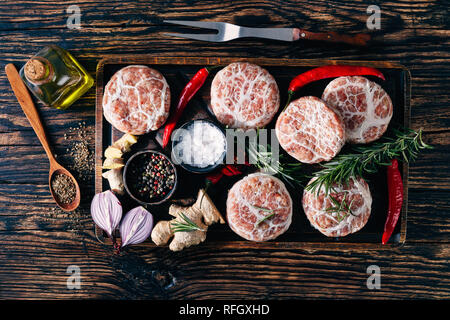 Fleisch Delicatessen - raw Atriaux von Schweinefleisch in caul Fett gewickelt, Schweizer Küche, Sorte Wurst auf einem hölzernen Fach mit Gewürzen und Salz, auf Holz Stockfoto