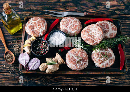 Fleisch-pastetchen - Rohstoff Schweizer Atriaux von Schweinefleisch in caul Fett gewickelt, Sorte Wurst auf einem hölzernen Fach mit Gewürzen und Salz, auf einen hölzernen Tisch, Blick fr Stockfoto