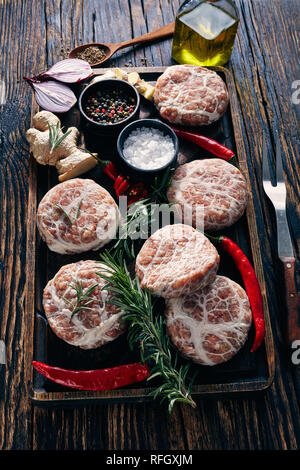 Fleisch-pastetchen-raw Atriaux von Schweinefleisch in caul Fett gewickelt, Schweizer Küche, Sorte Wurst auf einem hölzernen Fach mit Gewürzen und Salz, auf einem Holztisch Stockfoto