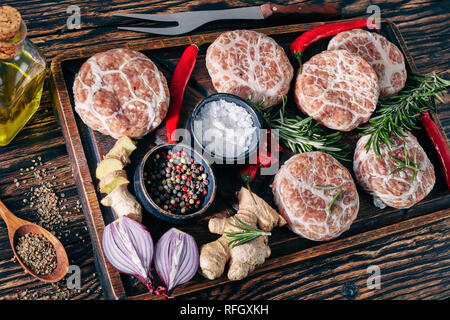 Close-up Fleischpflanzerl - raw Atriaux von Schweinefleisch in caul Fett gewickelt, Schweizer Küche, Sorte Wurst auf einem hölzernen Fach mit Gewürzen und Salz, auf einer Stockfoto