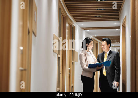 Geschäftsfrau erklärt Dokumente zu Happy chinesischen Kunden in der Bank Stockfoto
