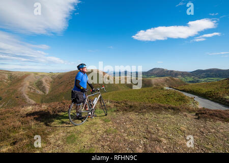 Eine männliche Radfahrer blickt auf den Shropshire Hills auf der Long Mynd in Church Stretton, Shropshire, England, Großbritannien Stockfoto