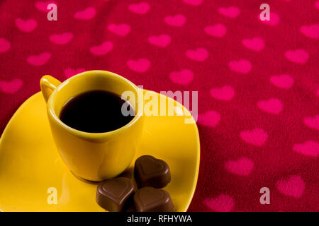 Tasse Kaffee und Schokolade auf Herz Hintergrund Stockfoto