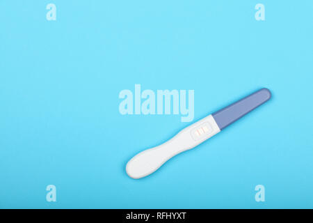 Nahaufnahme einer positiven (Schwangere) Ergebnis Schwangerschaft Test über pastell-blaue Papier Hintergrund, erhöhte hohen Winkel, direkt über Stockfoto