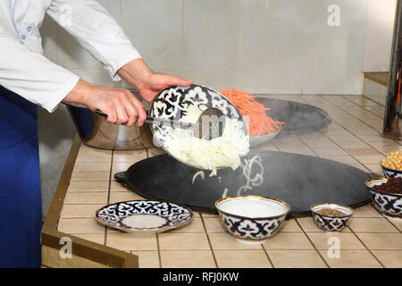 Kochen pilau in der Küche von ein orientalisches Restaurant. Gießt Zwiebeln im Kessel Stockfoto