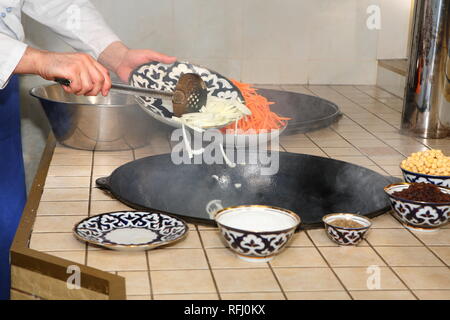 Kochen pilau in der Küche von ein orientalisches Restaurant. Gießt Zwiebeln im Kessel Stockfoto