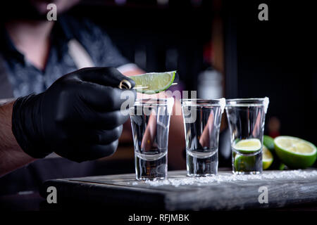 Barkeeper in schmückt tequila Kalk Schüsse. Mexikanische, Alkohol in Shot Gläser Stockfoto
