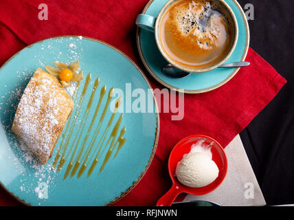 Apfelstrudel mit Eis auf deessrt Azure Teller und Tasse Kaffee Stockfoto