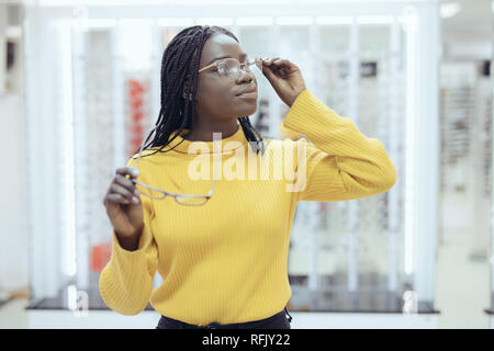 Junge afrikanische Frau kaufen, Brillen und die Wahl zwischen zwei Frames in Optiker Shop. Stockfoto