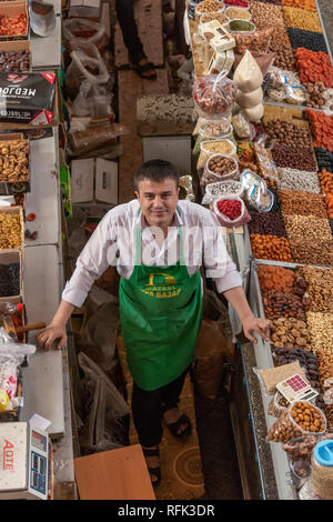 Der Mensch in grün Schürze Verkaufen getrocknete Früchte und Nüsse, Grün (Zelyony) Basar, Almaty, Kasachstan Stockfoto