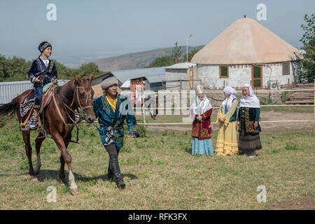 Kasachischen Mutter und Großmutter sehen einen Jungen lernen, ein Pferd zu reiten, Almaty, Kasachstan Stockfoto