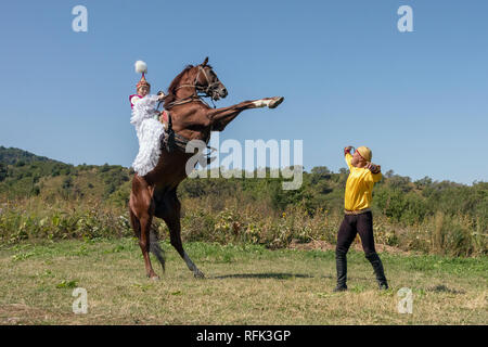 Kasachischen Frau in traditioneller Kleidung auf einem Pferd, Aufzucht von Almaty, Kasachstan Stockfoto