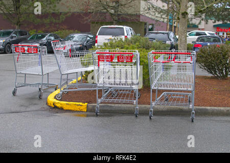 Abgebrochene Costco grocery Shopping Carts auf einem Parkplatz mit Autos im Hintergrund. Stockfoto