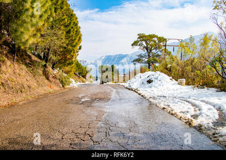 Bergauf Straße im Winter bei banikhet Dalhousie Himachal Pradesh Indien mit seitlich voller Schnee. Malerische winter Blick von der asphaltierten Straße mit s abgedeckt Stockfoto