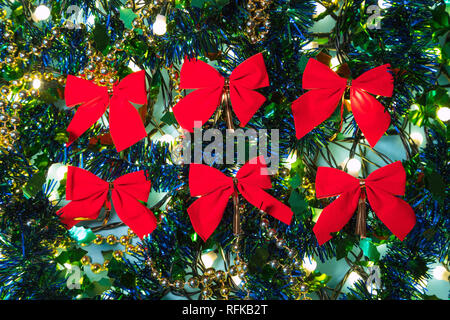 Red Ribbons zwischen Weihnachten Lichter und bunten Dekorationen im Hintergrund Stockfoto