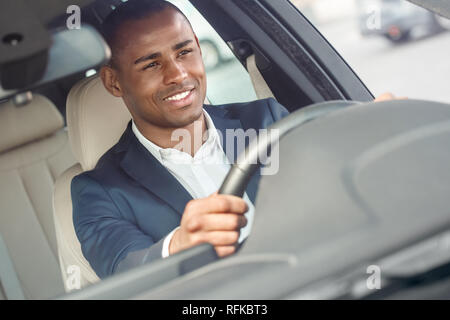 Junge Unternehmer Fahrer sitzt im Auto mit Lenkrad fahren gerne vorne außen Ansicht schließen Stockfoto