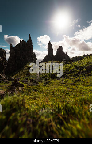 Alte Mann der Storr mit Gras im Vordergrund, helle Sonne, grüne Vegetation und Wolken an einem klaren Herbsttag (Isle of Skye, Schottland, Vereinigtes Königreich) Stockfoto