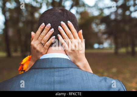 Frauen Arme um ein Männerkopf im Park an einem Tag Stockfoto