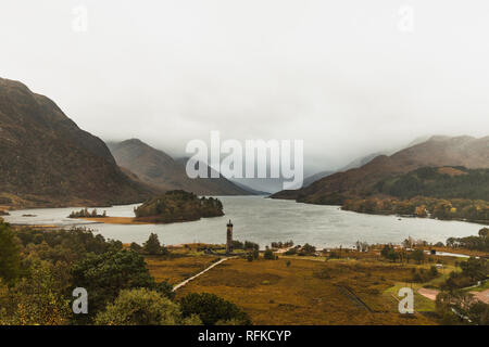 Blick auf Loch Shiel in Glenfinnan nahe dem glenfinnan Viadukt mit Glenfinnan Monument und Nebel bedeckte Berge im Herbst (Schottland, Europa) Stockfoto