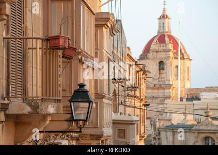 Die Häuserfassaden It-Telgha tal-Riemen Straße vor der Zitadelle mit St George's Basilika im Hintergrund. Stockfoto