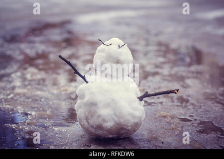 Feder Schneemann. Schneemann im Frühjahr schmutziger Schnee auf dem Hintergrund der Pfützen. dreckig Schneemann Stockfoto