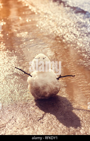 Feder Schneemann. Schneemann im Frühjahr schmutziger Schnee auf dem Hintergrund der Pfützen. dreckig Schneemann Stockfoto