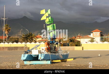 Grüne Boot mit Fahnen von der Sonne beschienen. Immigranten am Strand gelandet sind. Die bunten Boot am Strand gestrandet Stockfoto