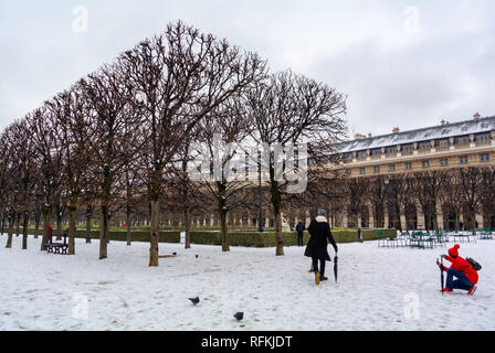 Ein Tourist, der ein Foto von einer Frau im Palais Royal Garten unter Schnee, Paris, Frankreich Stockfoto
