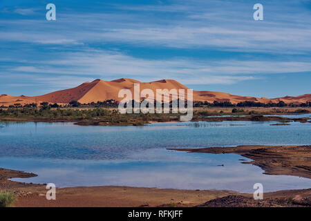 Ein Sandhügel (Düne) von Erg Chebbi und Reflexion auf See. Landschaftsaufnahme in der Nähe der Stadt Merzouga, Sahara-Wüste, Marokko im November. Stockfoto