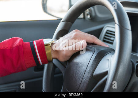 Die Männer Hand mit einer Uhr am Lenkrad eines modernen Autos Stockfoto