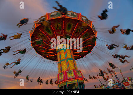 Kinder genießen eine gigantische Schaukel Fahrt an einem lokalen Karneval. Stockfoto