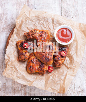 Gebratene barbeque Chicken Wings mit BBQ Sauce, italienische Kräuter, Olivenöl und Pfeffer, Ansicht von oben Stockfoto