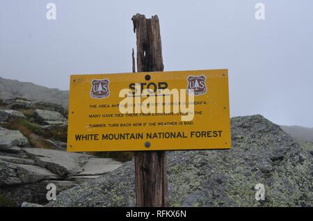 Warnschild auf der Ammonoosuc Schlucht Trail, die besagt, dass der Bereich unter dem schlechtesten Wetter in Nordamerika, und Warnungen Wanderer, dass viele gestorben sind, beim Wandern die Trail, in den White Mountains, New Hampshire, USA, Dezember, 2018. () Stockfoto