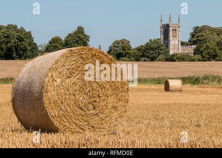 Runde Strohballen auf einem Feld in der Nähe von All Saints Church, Aldwincle, Northamptonshire Stockfoto