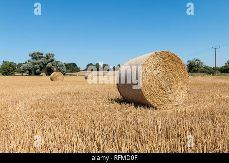 Runde Strohballen auf einem Feld in der Nähe von All Saints Church, Aldwincle, Northamptonshire Stockfoto