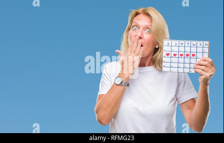 Mittleres Alter blonde Frau mit Menstruations Kalender ver isoliert Hintergrund decken den Mund mit der Hand mit Schande für den Fehler, den Ausdruck von Angst schockiert Stockfoto