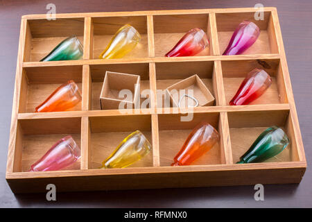 Bunte kleine Flaschen und kleinen Kartons in einer Holzkiste in der Ansicht Stockfoto